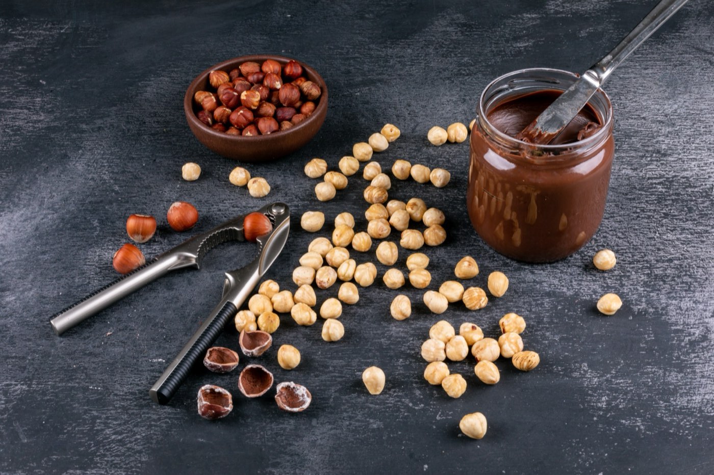 Blanched hazelnuts beside a jar of nut paste