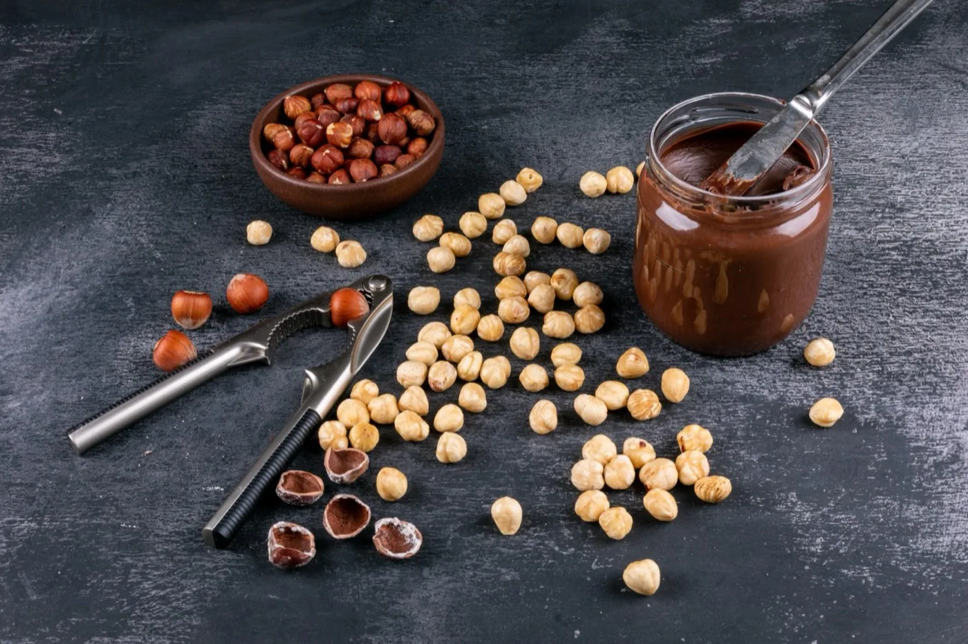 Blanched hazelnuts beside a jar of nut paste